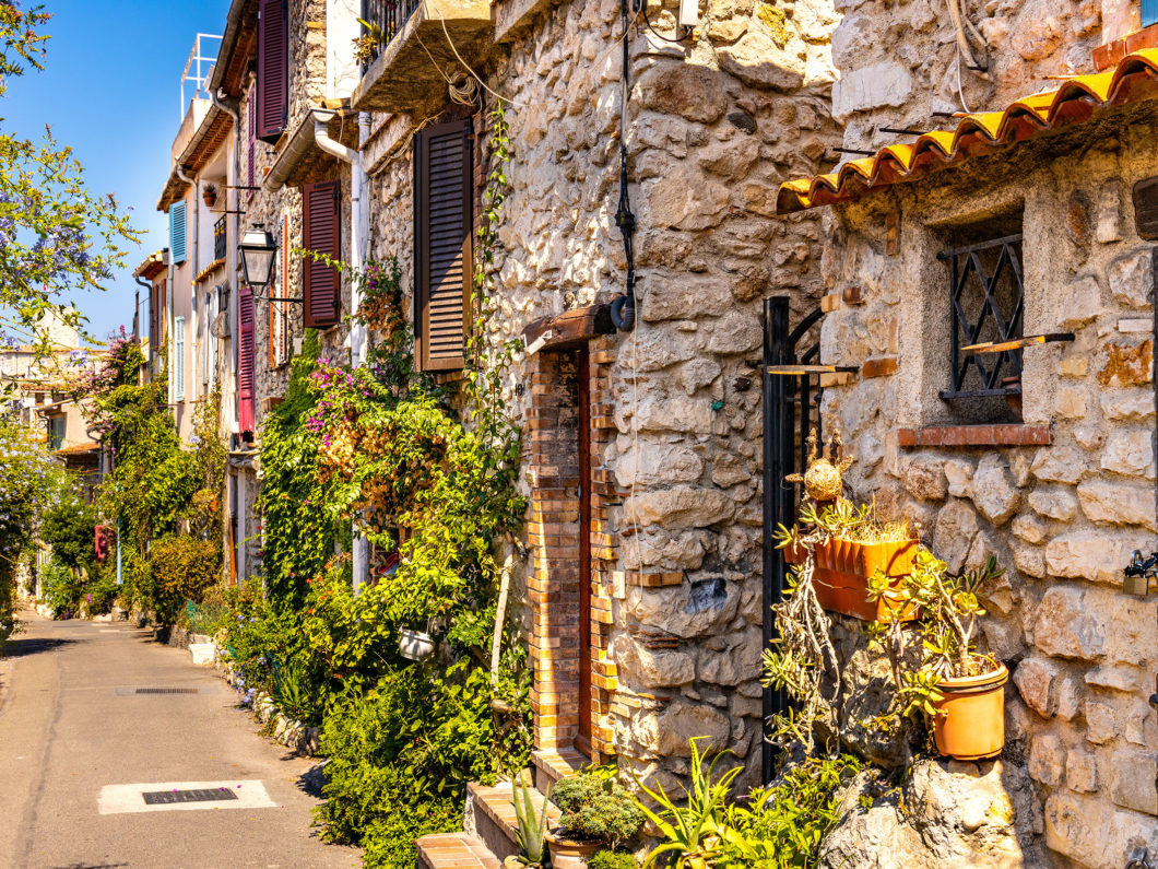 Antibes, France   August 4, 2022: Rue des Revennes street with colorful vintage houses in historic old town of Antibes resort city onshore Azure Cost of Mediterranean Sea