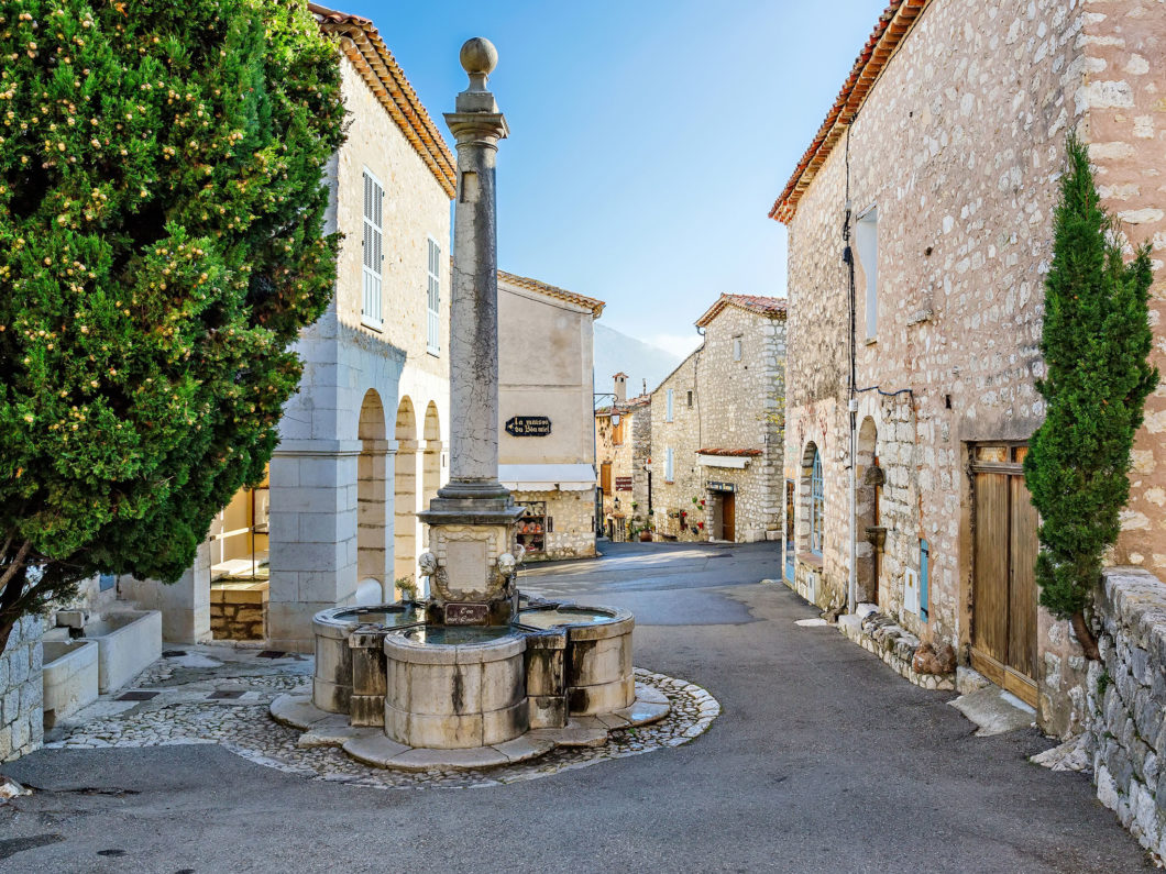 Medieval street with a fountain in the village Gourdon, France